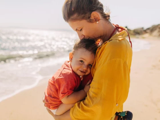 Photo of mother hugging her baby boy while enjoying together at the beach