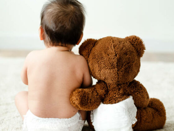 Back of a baby with a teddy bear